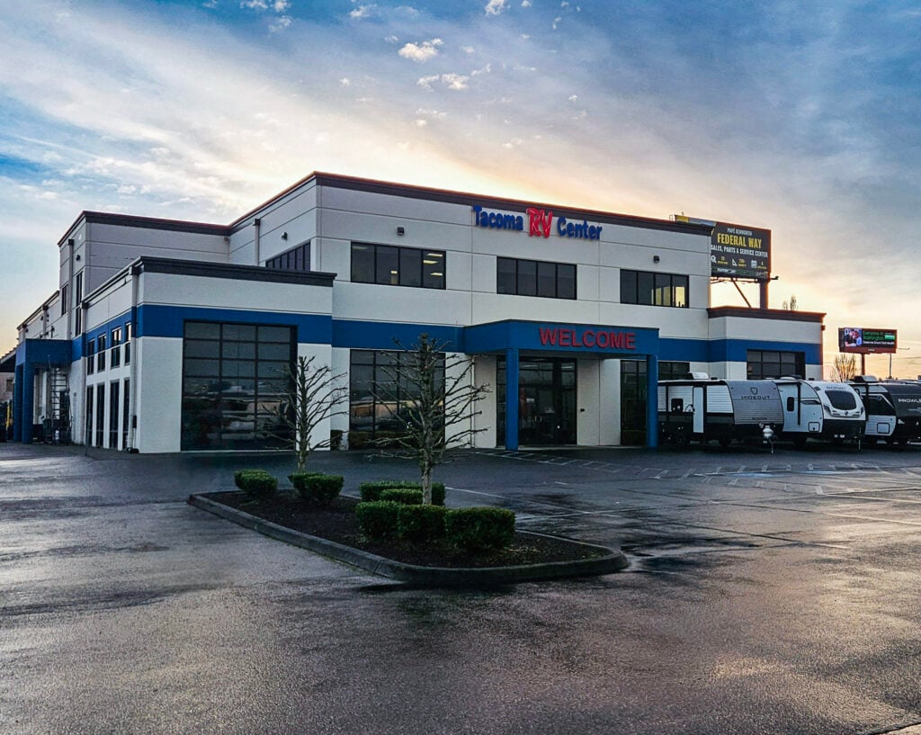 Daytime photo of Tacoma RV Center in Tacoma, Washington, showing the RV dealership lot with recreational vehicles parked in front of the main building and business signage visible