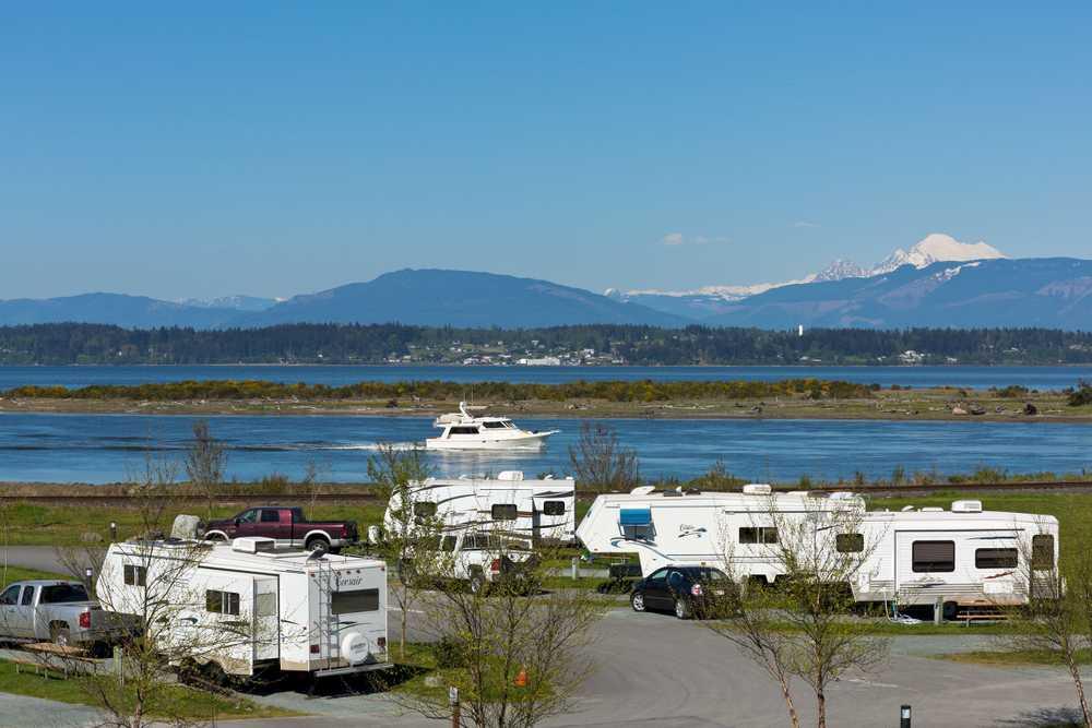 Waterfront RV park in Puget Sound Washington with travel trailers overlooking the bay and mountain views, offering scenic coastal camping with hookups