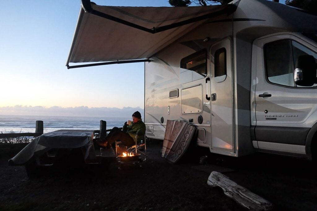 Beachfront RV camping in Washington state with a camper van overlooking the Pacific Ocean, campfire setup, and sunset views along the Washington coast.