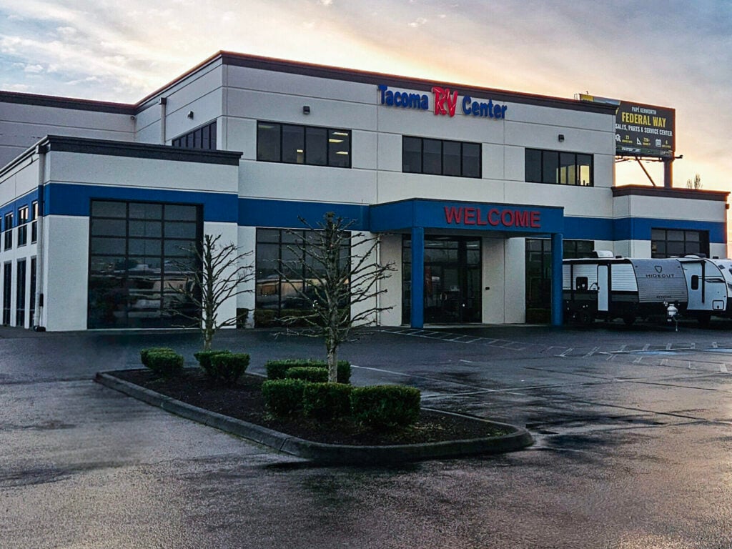 Daytime photo of Tacoma RV Center in Tacoma, Washington, showing the RV dealership lot with recreational vehicles parked in front of the main building and business signage visible