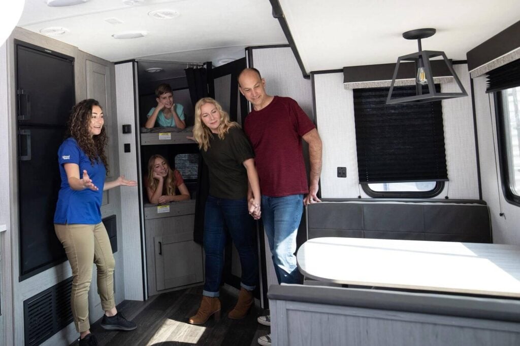 Family touring the inside of a modern travel trailer with an RV sales representative in Washington State.