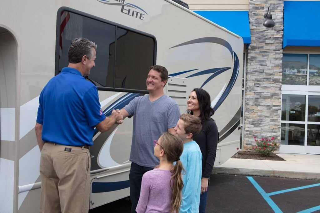 Family shaking hands with an RV dealership representative after purchasing a fifth wheel camper in Washington State.