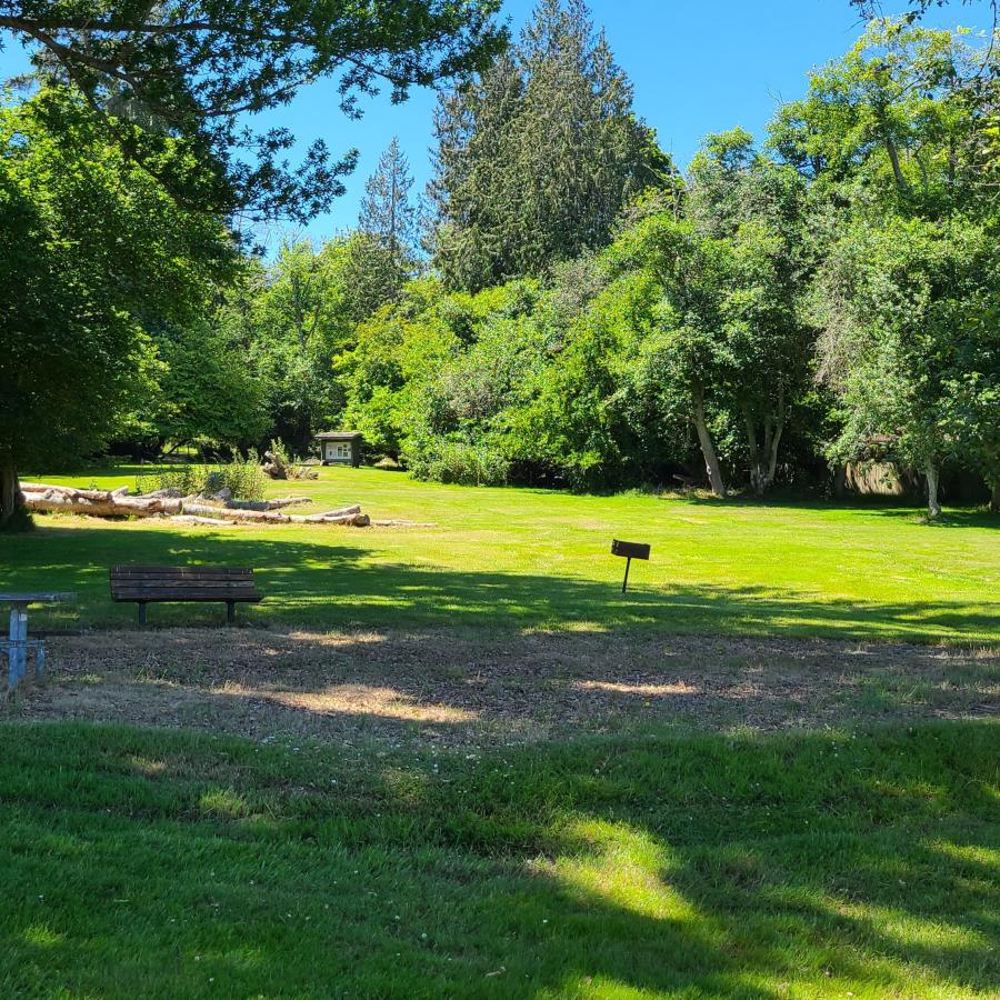 Open grassy day-use area surrounded by lush trees on Blake Island, featuring peaceful picnic and recreation spaces near popular Puget Sound RV camping destinations for Summer 2026.