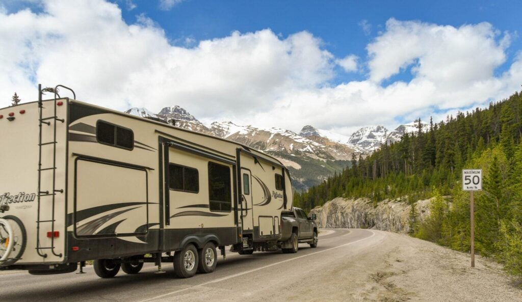 Travel trailer being towed through scenic mountain roads near Mount Rainier National Park, highlighting RV towing safety and towing capacity tips for Washington camping trips.