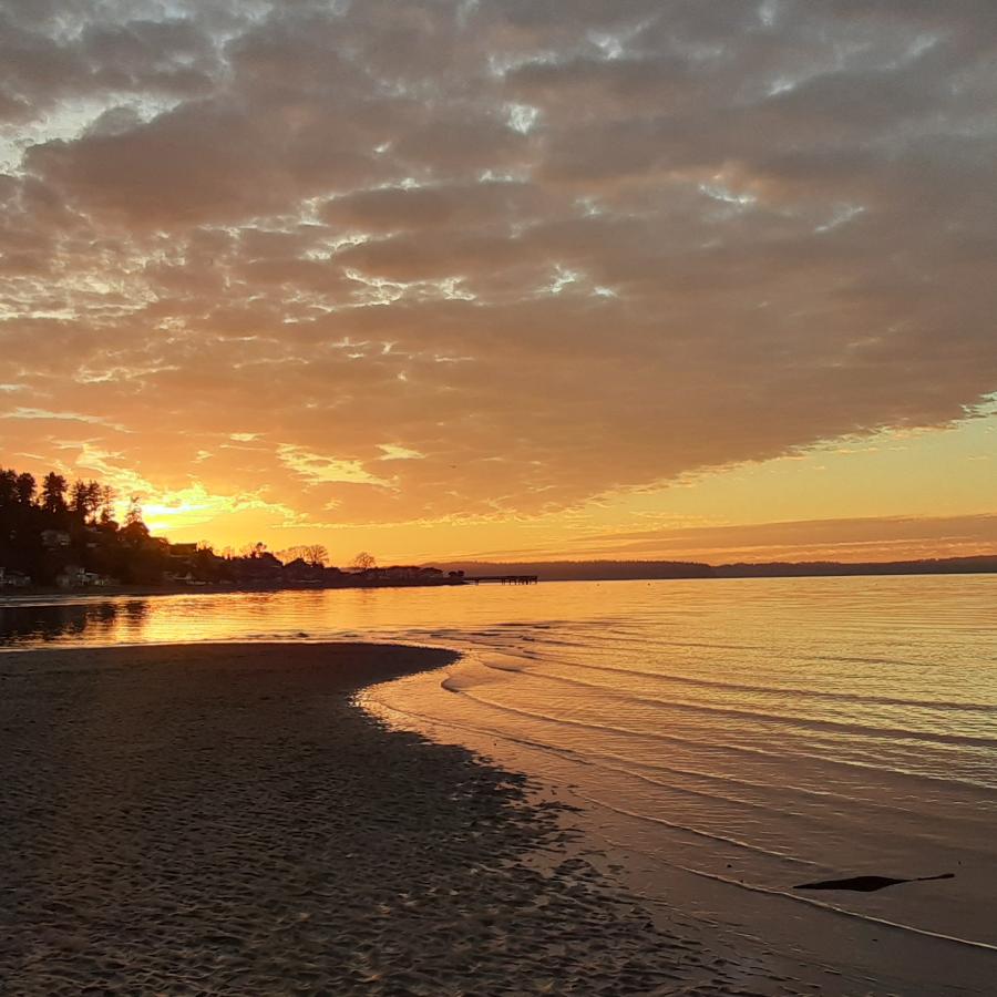 Colorful sunset over the calm shoreline at Dash Point State Park with gentle waves and sandy beach, highlighting beautiful evening views near Puget Sound RV camping destinations.
