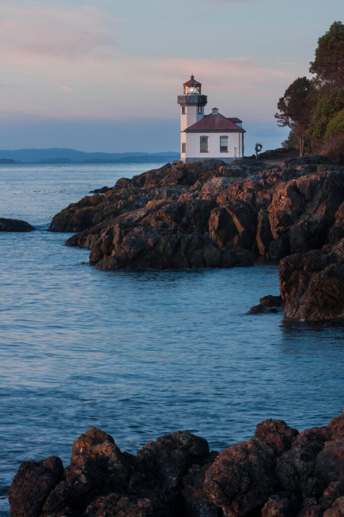 Lime Kiln Lighthouse overlooking the rocky coastline and ocean in the San Juan Islands of Washington State during sunset.