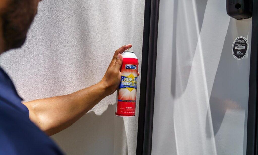 Applying rubber seal conditioner to an RV slide-out during spring RV maintenance preparation for summer camping in Washington.