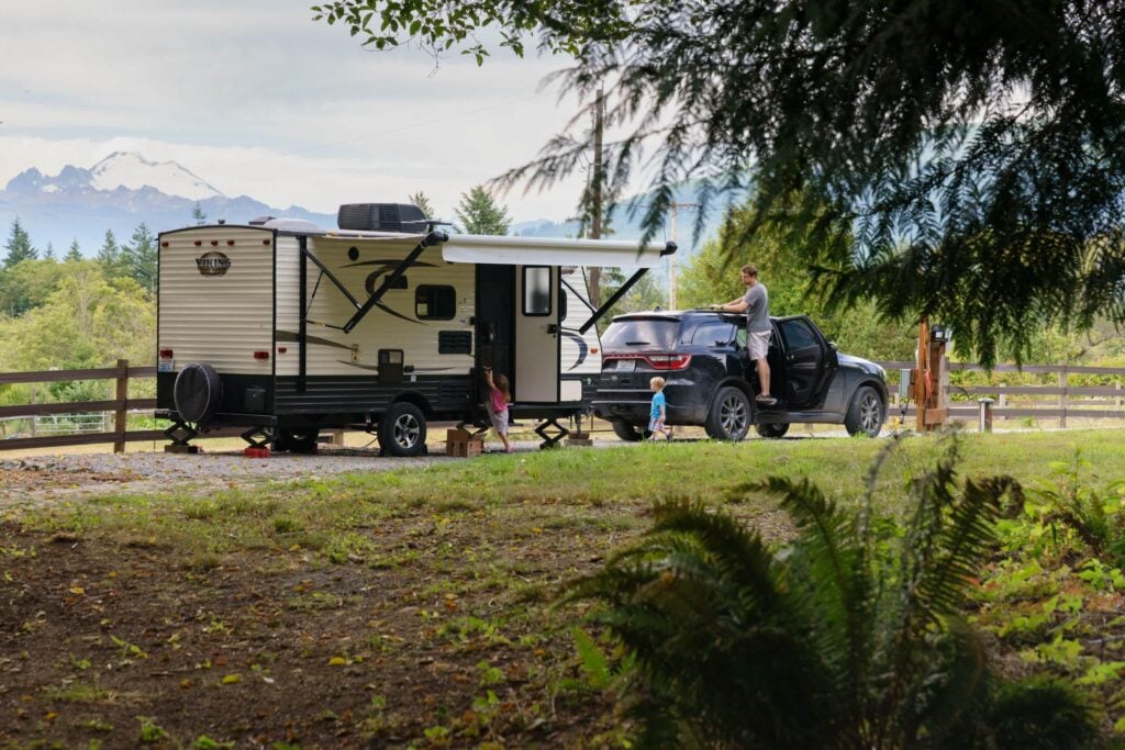 Family camping beside a travel trailer in a wooded Washington State campground during a Pacific Northwest RV trip.