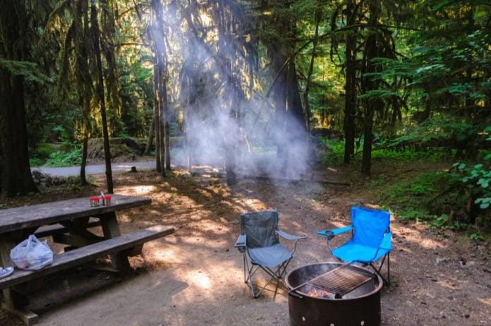 Forest campsite with campfire ring and camping chairs near Mount Rainier RV camping destinations in Washington State.