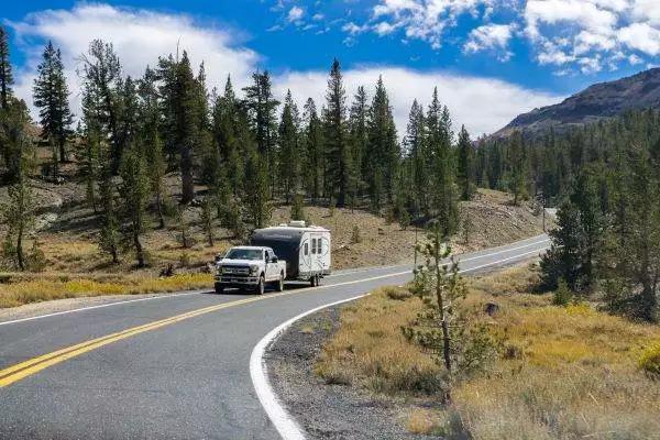 Compact travel trailer driving through forest roads near Mount Rainier with proper tow vehicle setup and safe RV towing practices.