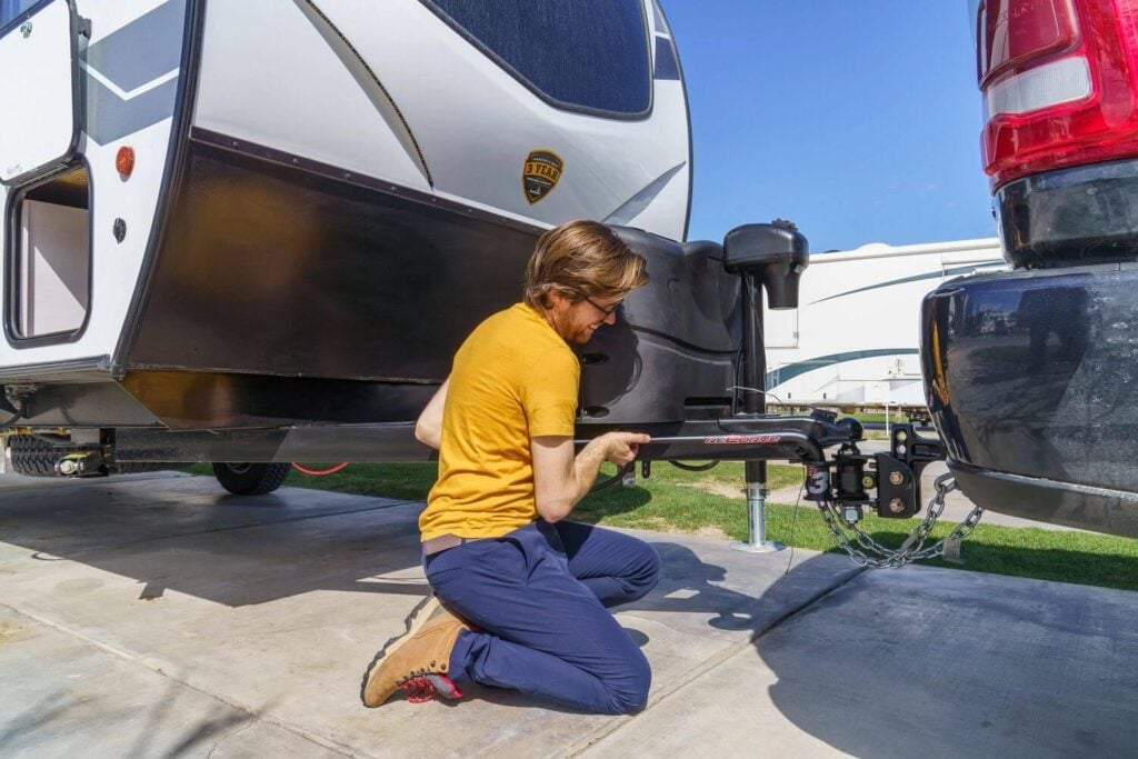 Inspecting and adjusting a travel trailer weight distribution hitch during spring RV maintenance preparation.