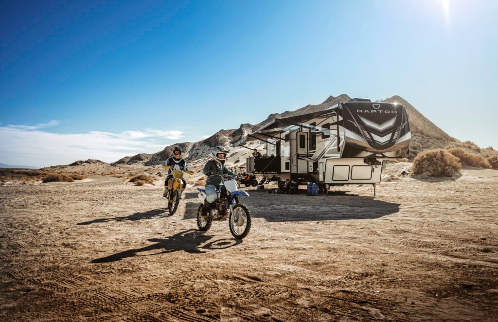 Toy hauler RV parked in a desert campsite with dirt bikes, demonstrating adventure-ready RV options for first-time RV buyers seeking outdoor recreation and off-grid travel.