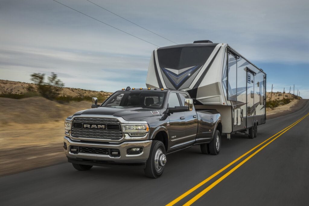 Heavy-duty Ram truck towing a luxury fifth wheel RV on an open highway for RV Towing 101 towing capacity and truck matching guide.