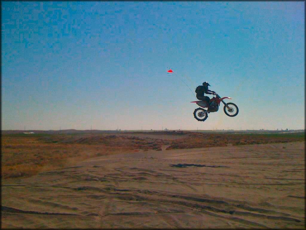 Motocross rider performing a jump in an off-road riding area, showcasing outdoor powersports adventures perfect for toy hauler travel.